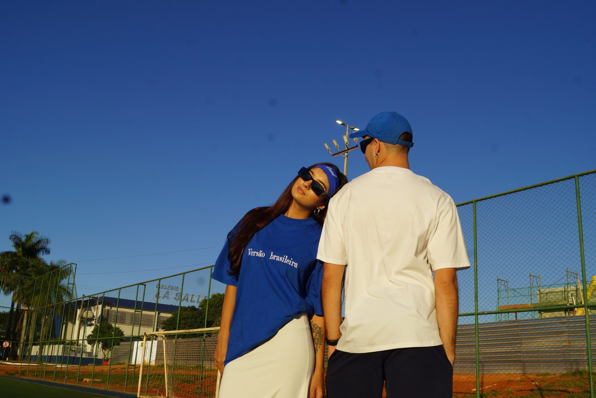 Casal encostado um no outro no fim de tarde, camiseta azul e branca