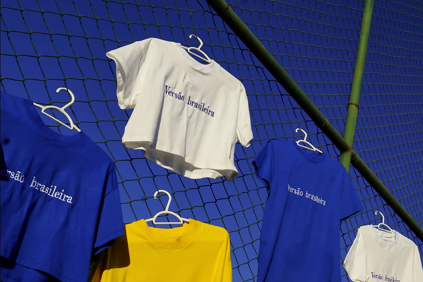 Camisetas Versão Brasileira penduradas no alambrado do campo, ao entardecer