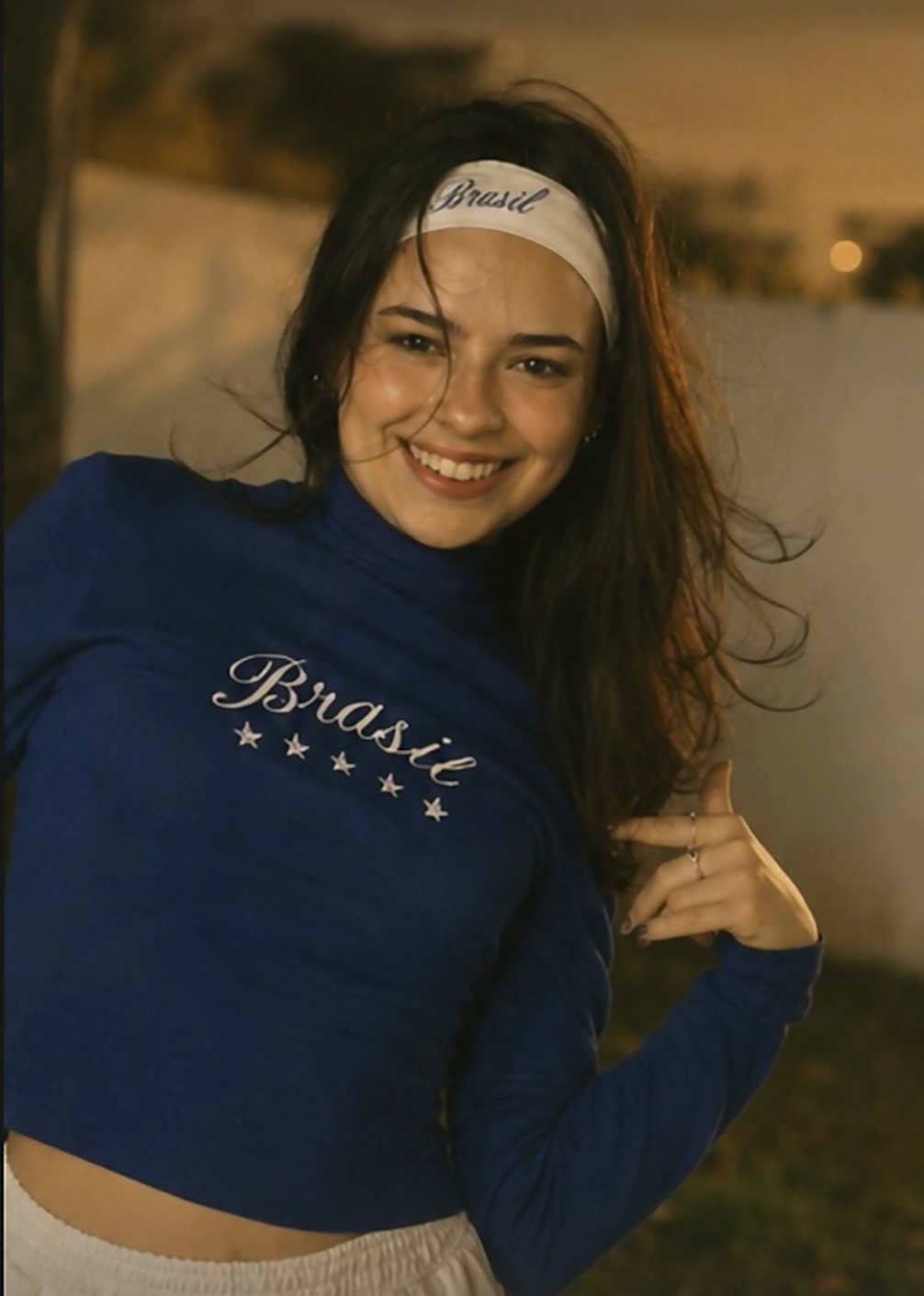 Retrato sorrindo, blusa de manga longa com 'Brasil' bordado e faixa de cabelo