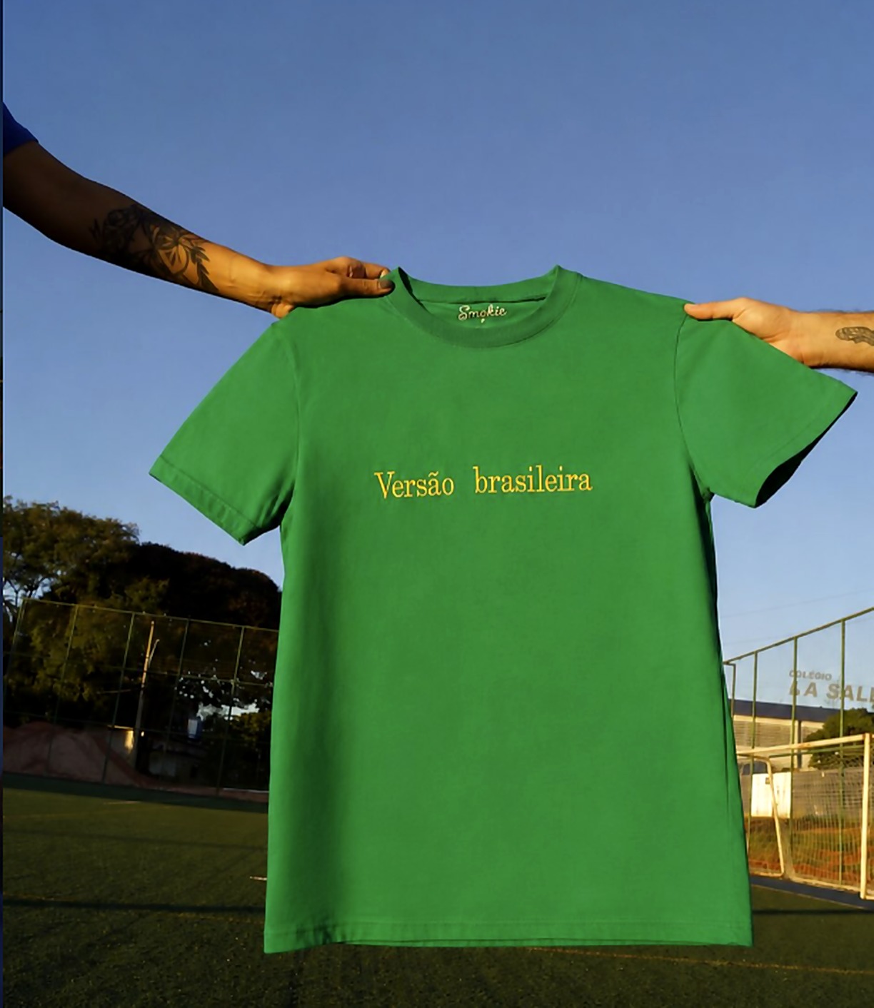 Camiseta verde Versão Brasileira erguida contra o céu